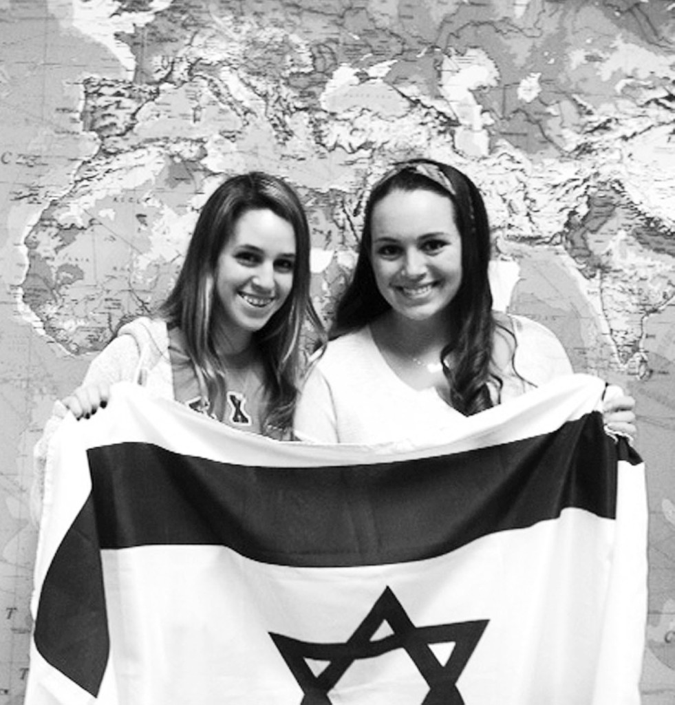 Seniors Mallory Lustbader (left) and Dani Shwachman (right) pose in front of a map with an Israeli flag to commemorate their trip to help Ethiopian Jews move to Israel in February. They finished moving 73 people from Ethiopia to Israel on February 18. Photo illustration by Maddy Placik.