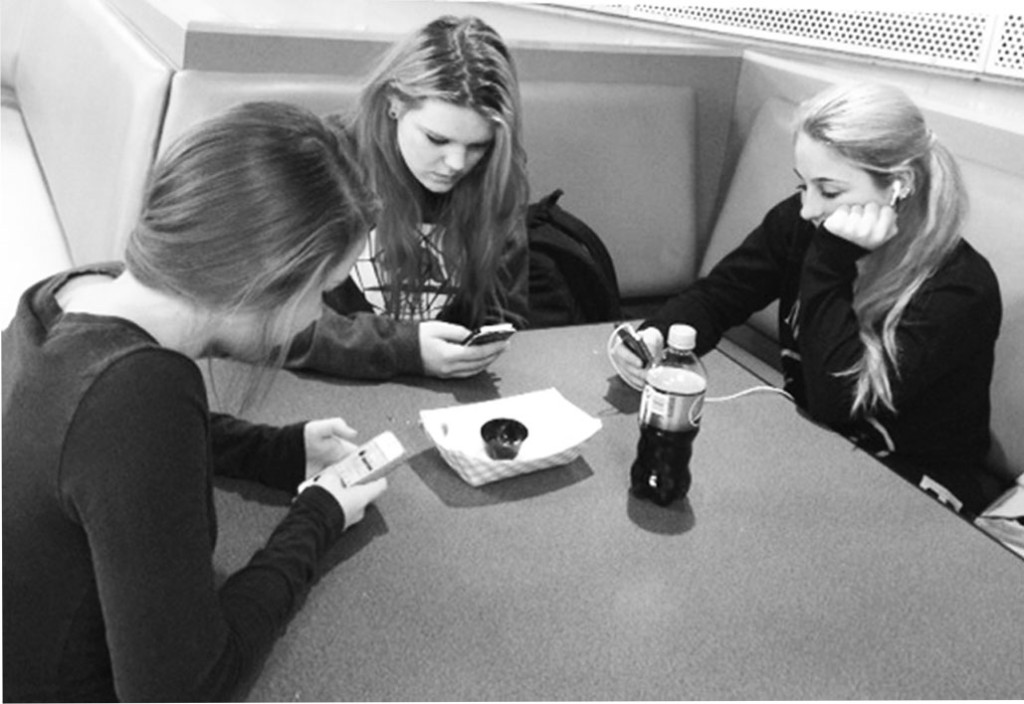 Freshmen Samantha Bell (left), Katie Whalen (center) and Zoe Moretta (right) said that using technology at lunch is a frequent occurrence when they eat together.  Photo by Caroline Rabin.