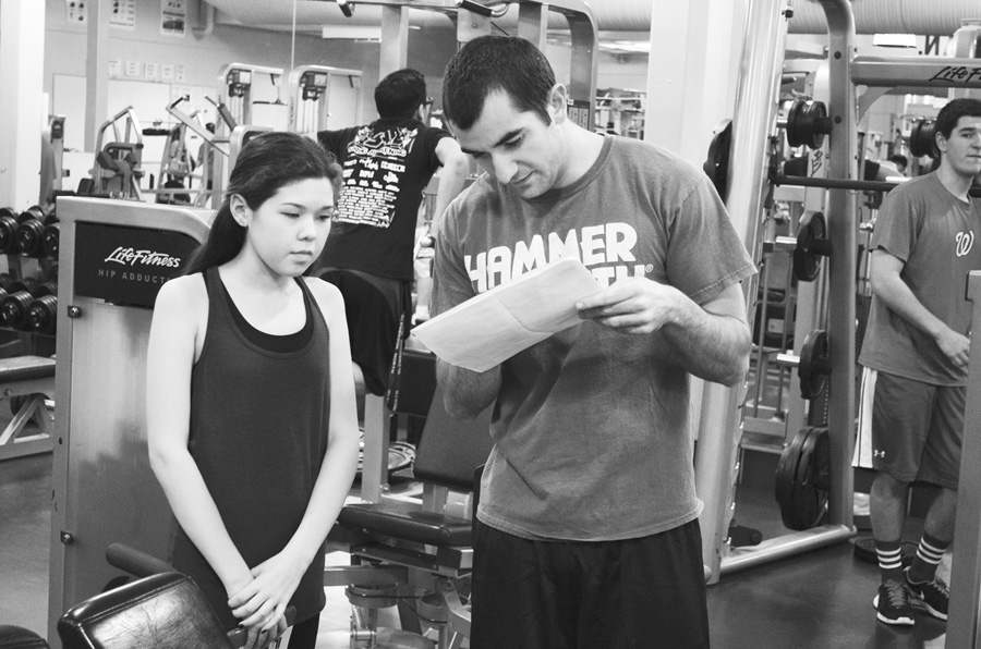 Coach Justin Cooper discusses a workout with freshman Hannah Levy. The girls have been participating in preseason workouts since December, and the indoor season started Jan. 26. Photo by Gabe Weininger