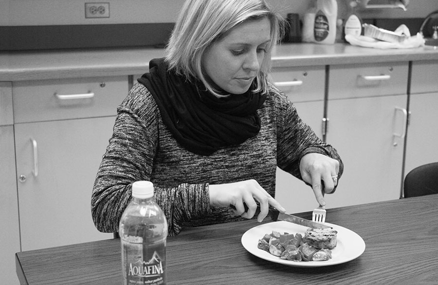 Spanish teacher Samantha Rinella eats a grilled pork chop with garlic, roasted sweet potatoes, Brussel sprouts and bacon with shallot dressing. The meal consisted of various foods she could eat while on the paleo diet. Photo by Anisha Thotam