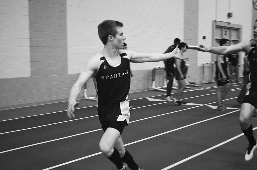 Junior Scott Thomas takes the handoff from a teammate during the indoor track and field conference meet on March 20. In the race, the relay team finished in first place with a time of 8:37.30, helping the track team win indoor conference. Photo by Caroline Smith