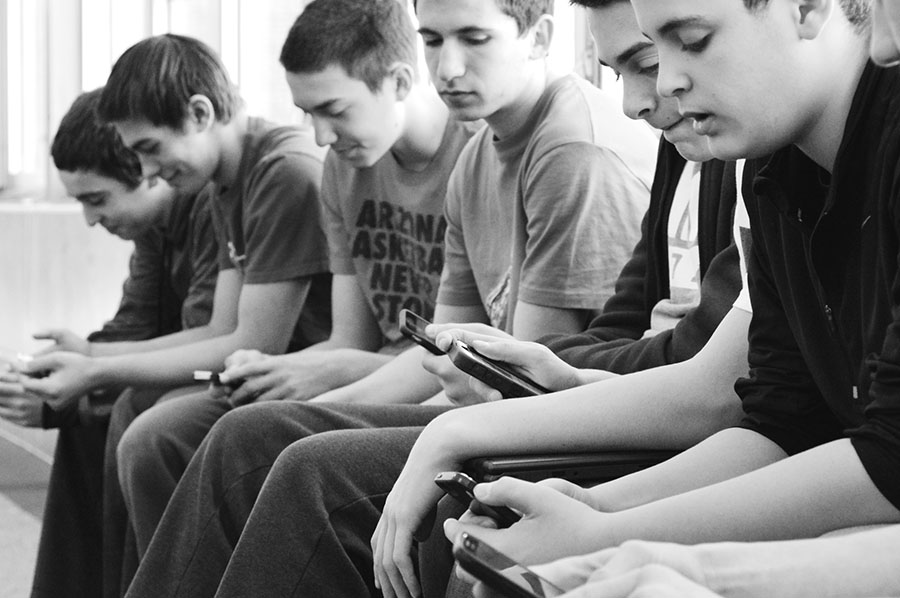 Freshmen use their phones in the Student Activities Hallway. Cell phones and Wi-Fi routers could potentially cause cancer by emitting radio-frequency radiation that could be absorbed by nearby students. Photo by Megan Cruz