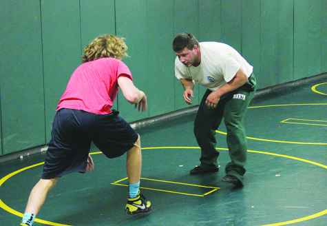 Wrestling Head Coach Jason Erwinski practices with junior Jake Fahey during an early morning workout. The team practices before school five times a week. Photo by Emma Kawasaki.