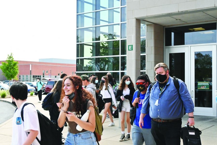 Junior Elani Torres takes off her mask while leaving the building after school. Students are encouraged but not required to maintain a proper social distance of three feet when unmasked and outside. Photo by Saruul-Erdene Jagdagdorj