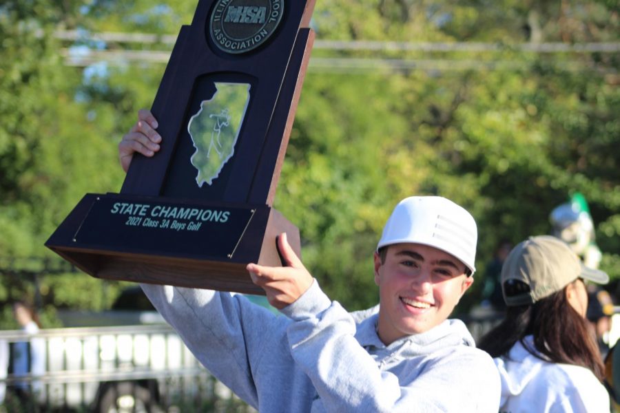 State+champion+Jason+Gordon+hoists+the+boys+golf+state+championship+trophy+before+walking+in+the+Homecoming+parade+on+Oct.+17.+Gordon+won+state+as+an+individual%2C+shooting+137+over+two+rounds+and+tying+the+state+series+record.+The+team+shot+575+over+two+rounds%2C+winning+state+while+breaking+the+previous+record.+Photo+by+Kate+Leverenz