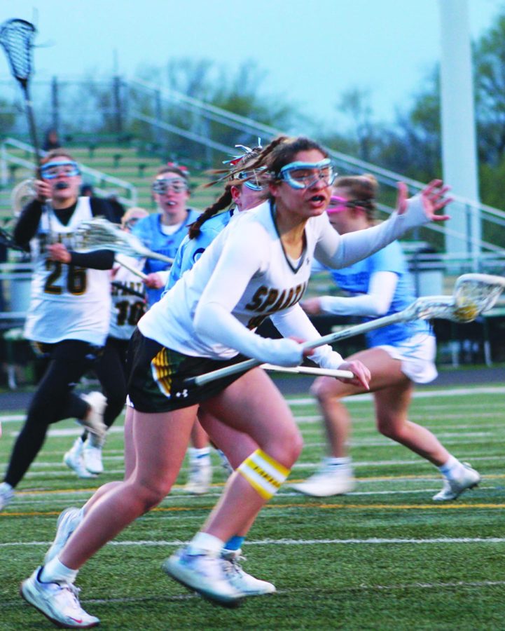 Junior+Rachael+Rizzi+runs+with+the+ball+while+protecting+her+stick+in+a+game+against+DePaul+College+Prep+on+April+24.+The+Spartans+lost+the+game+8-7.+Photo+by+Chase+Goldstein