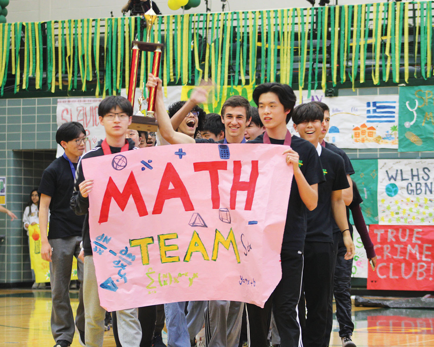 Math team members hold a poster and the first place trophy from the Illinois Council of Teachers of Mathematics State Math Contest during the Pride Assembly on April 26. 