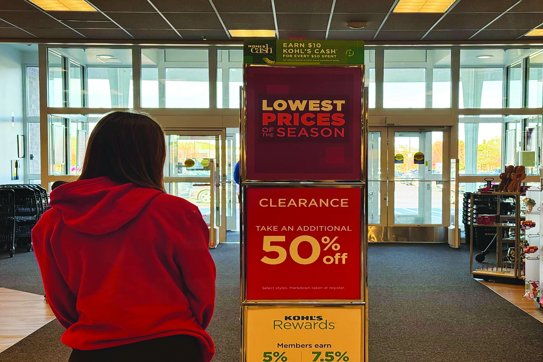 A shopper looks at discount signs near the entrance of a department store. Discounts are commonly implemented by marketing teams to appeal to consumer psyche and encourage impulsive purchases.  