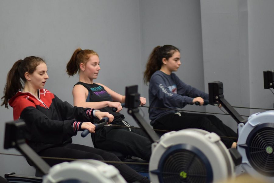 Sophomore Abby Schyman (center) and junior Nikki Nemerson (left) practice in the Dammrich Rowing Center in Skokie on March 4. North Suburban Crew uses the Dammrich Rowing Center when the weather does not permit the team to practice on the Skokie Lagoons. Photo by Natalie Sandlow