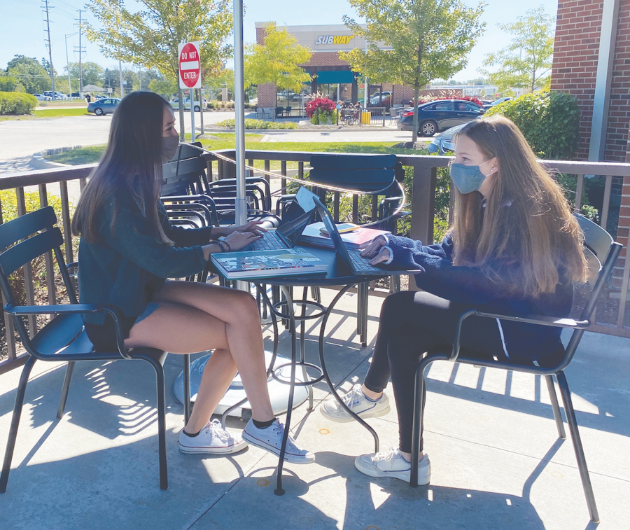 In a staged photo, yearbook Editors-in-Chief Ceci Santellano (left) and Jamie Resis talk. The yearbook is planned to look different this year compared to previous years due to COVID-19. Photo by Rachel Cha