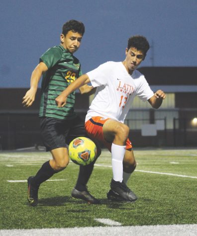 Battling an opposing player, junior Marco Coronado (left) fights for a loose ball in a game against Latin on Oct. 9. The game ended in a 3-3 tie, with both teams scoring once in the last five minutes of the game.  Photo by Jiya Sheth