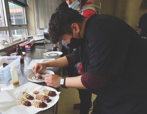 In one of the baking and pastries class, sophomore Max Wadhwa places a fresh cranberry biscotti dipped in milk chocolate and drizzled in white chocolate on his plate. Wadhwa spends almost every day in the culinary room, either training for culinary competitions or in culinary class focusing on plating techniques.