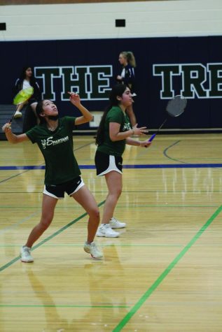 Winding up for a smash, freshman Katelyn Wu (left) and her doubles partner Nicole Konstant play at the conference tournament on April 30. The team placed second at the sectional competition with a score of 13.5 on May 5. Photo by Jiya Sheth