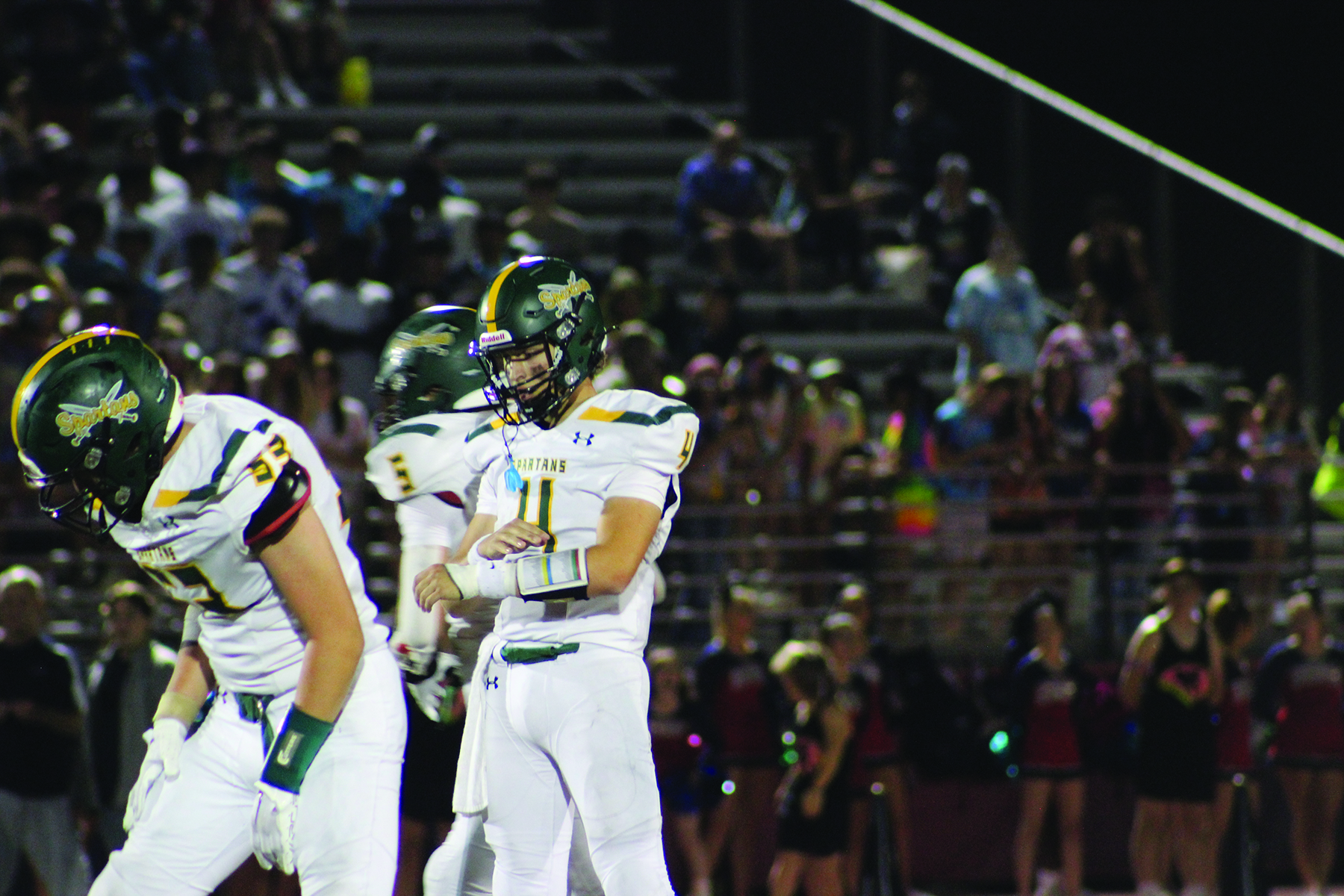 Sophomore JJ Schlenhardt reviews plays on his wristband before the snap in a game against Conant on Sept. 9. This was Schlenhardt’s third game of the season as quarterback before his injury during the Rolling Meadows game on Sept. 15. 