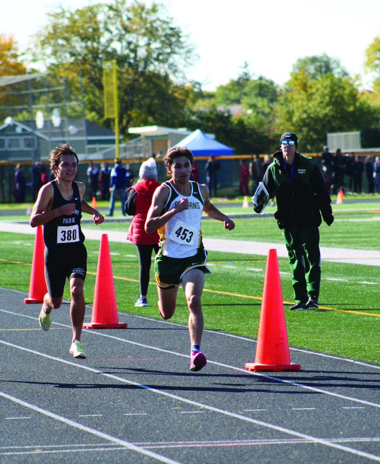 In the last 100 meters in the varsity 3-mile race, junior John Ihrke (right) outruns his competitor at the conference meet on Oct. 15. Ihrke finished seventh with a time of 15:38. Photo by Jiya Sheth.