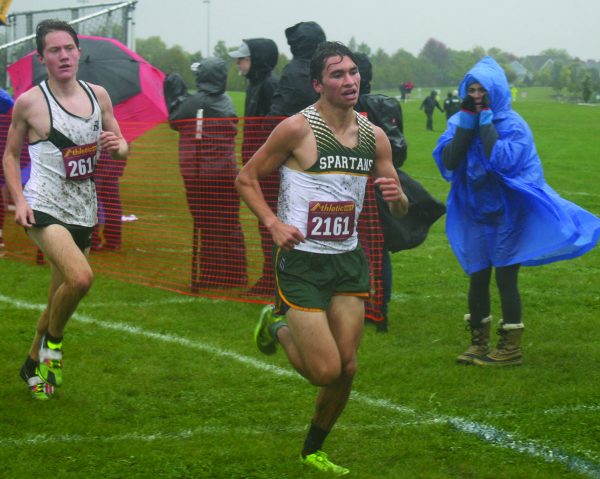 Running through the rain, senior John Ihrke overtakes his New Trier opponent during the conference meet at Vernon Hills on Oct. 14. Ihrke placed fourth in the 3-mile race with a time of 16:33. Photo by Karsten Konstant. 