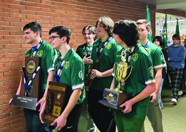 The boys bowling team walks through the halls in a school-organized parade, celebrating season accomplishments. Junior Josh Sachs (front left) holds the team’s third place state trophy. Photo by Karsten Konstant