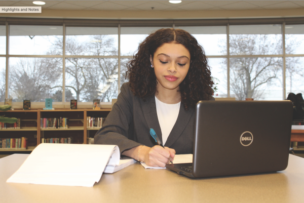 Senior Gabriella Carr poses with her study materials for the Illinois Real Estate Exam. Carr plans on taking the exam shortly after high school graduation. After passing the exam, Carr can become a licensed real estate agent. Photo by Ruby Werber