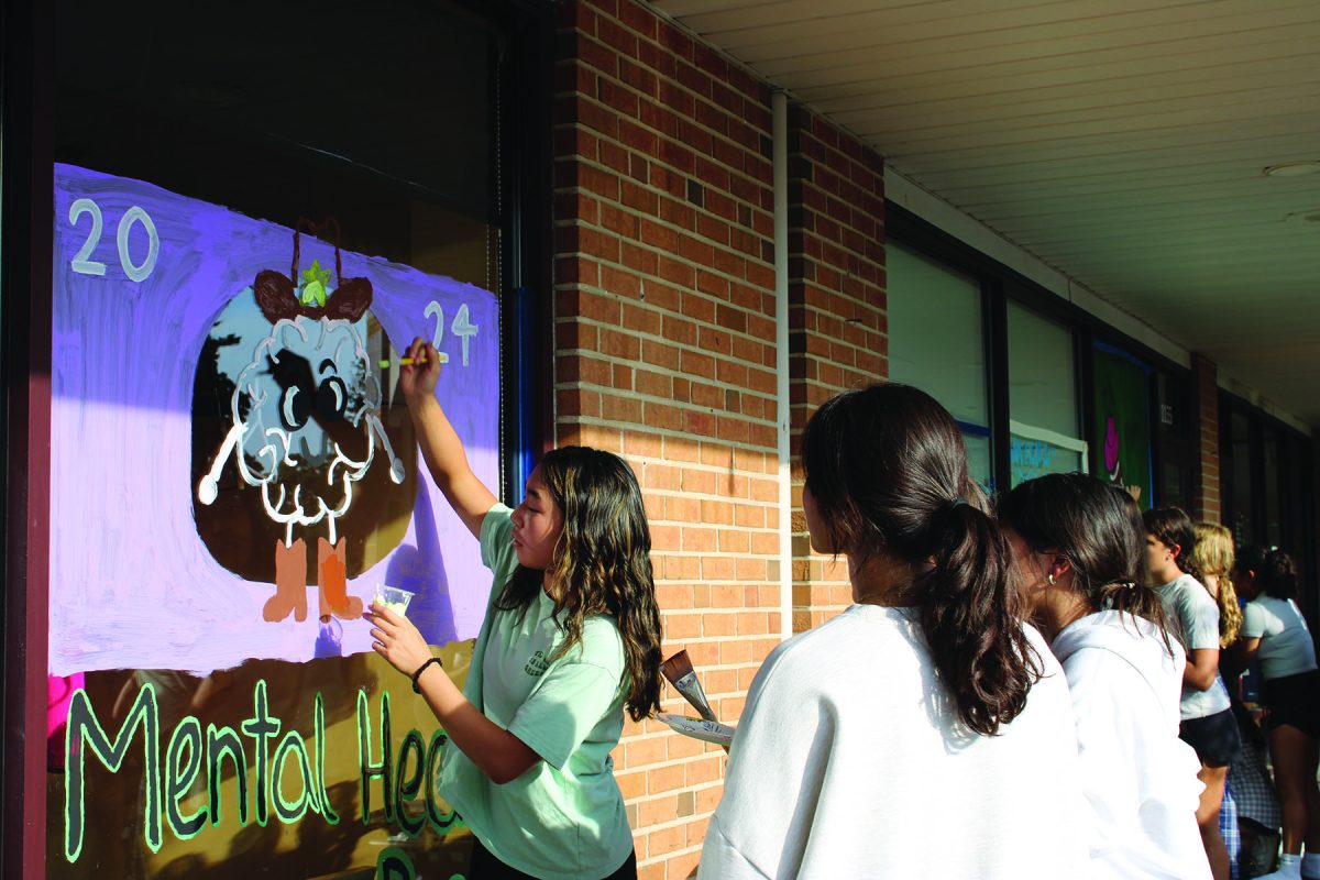 Sophomore Olivia Park decorates a window at Paint the Town for Mental Health Advisory Board. Both the SEL survey and the Mental Health Advisory Board seek to support student well-being. 