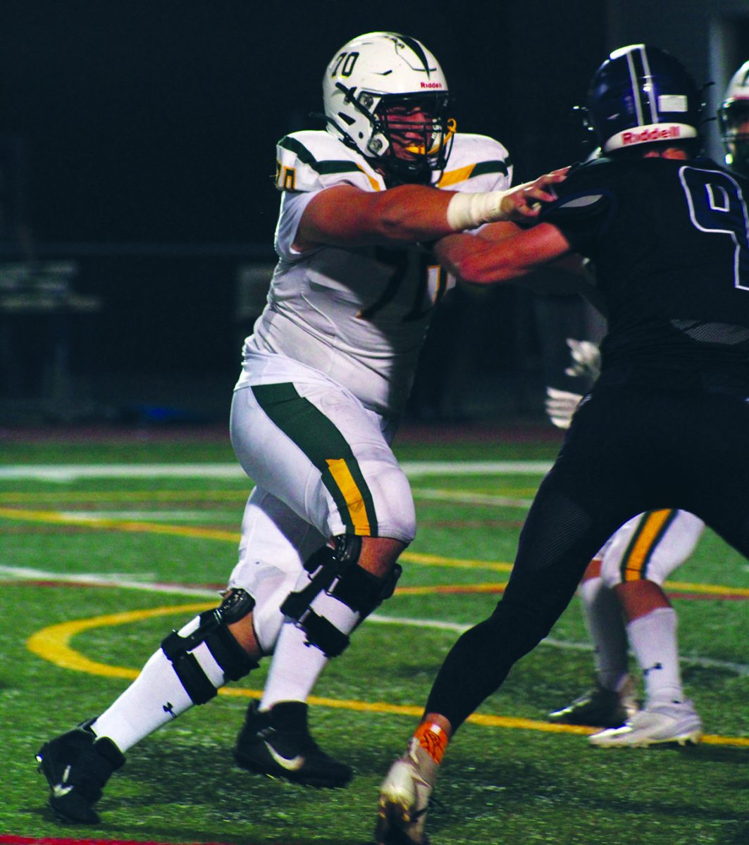 Senior Cray Paich blocks a Rolling Meadows opponent on Sept. 13. The Spartans lost 42-34. Linemen work during the offseason to build their strength. Photo by Cailyn Kelsen