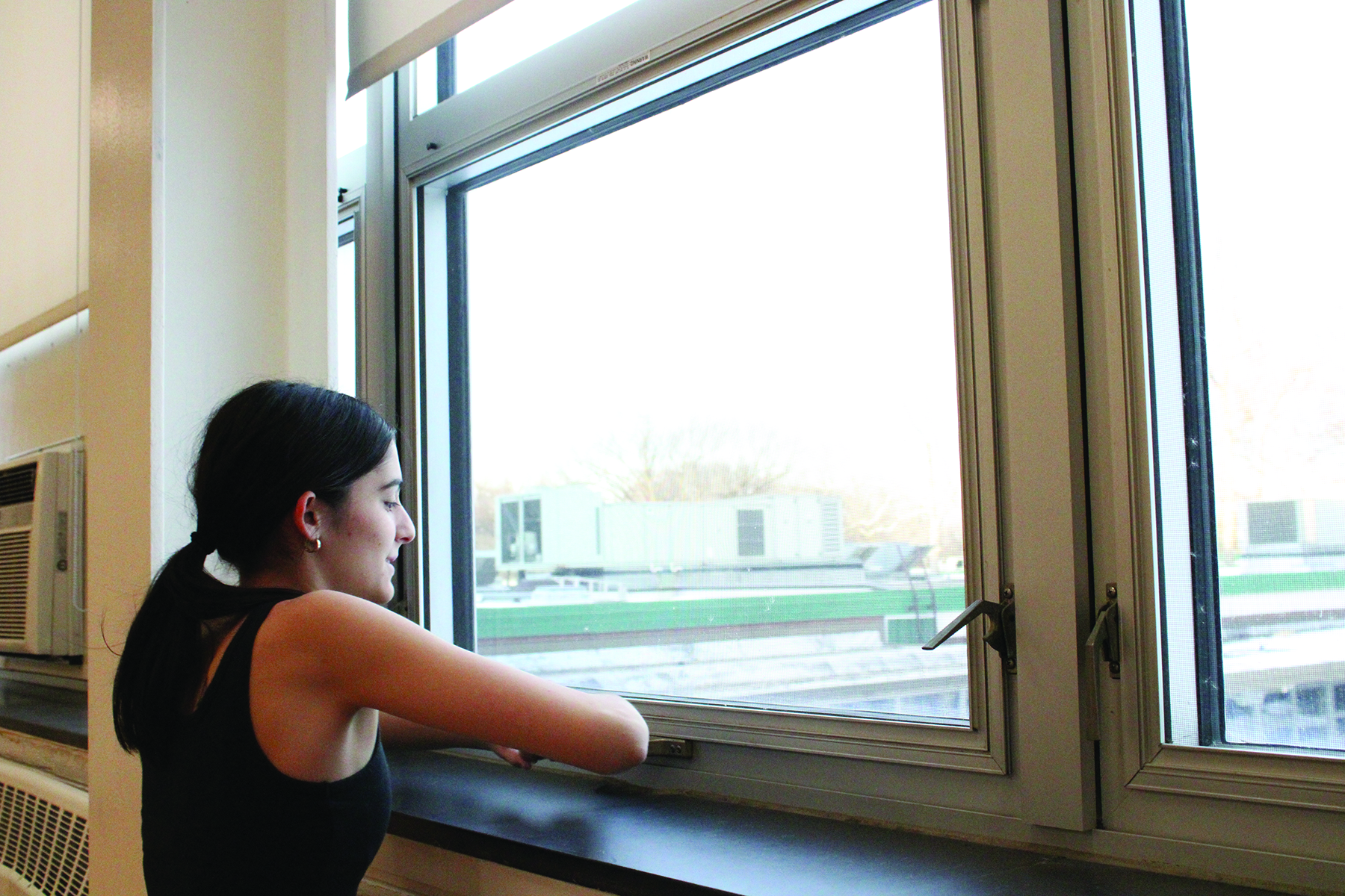 Junior Kate Dalinka opens a window to combat the heat in the dance studio during poms practice. Research suggests that elevated classroom temperatures can impede focus.