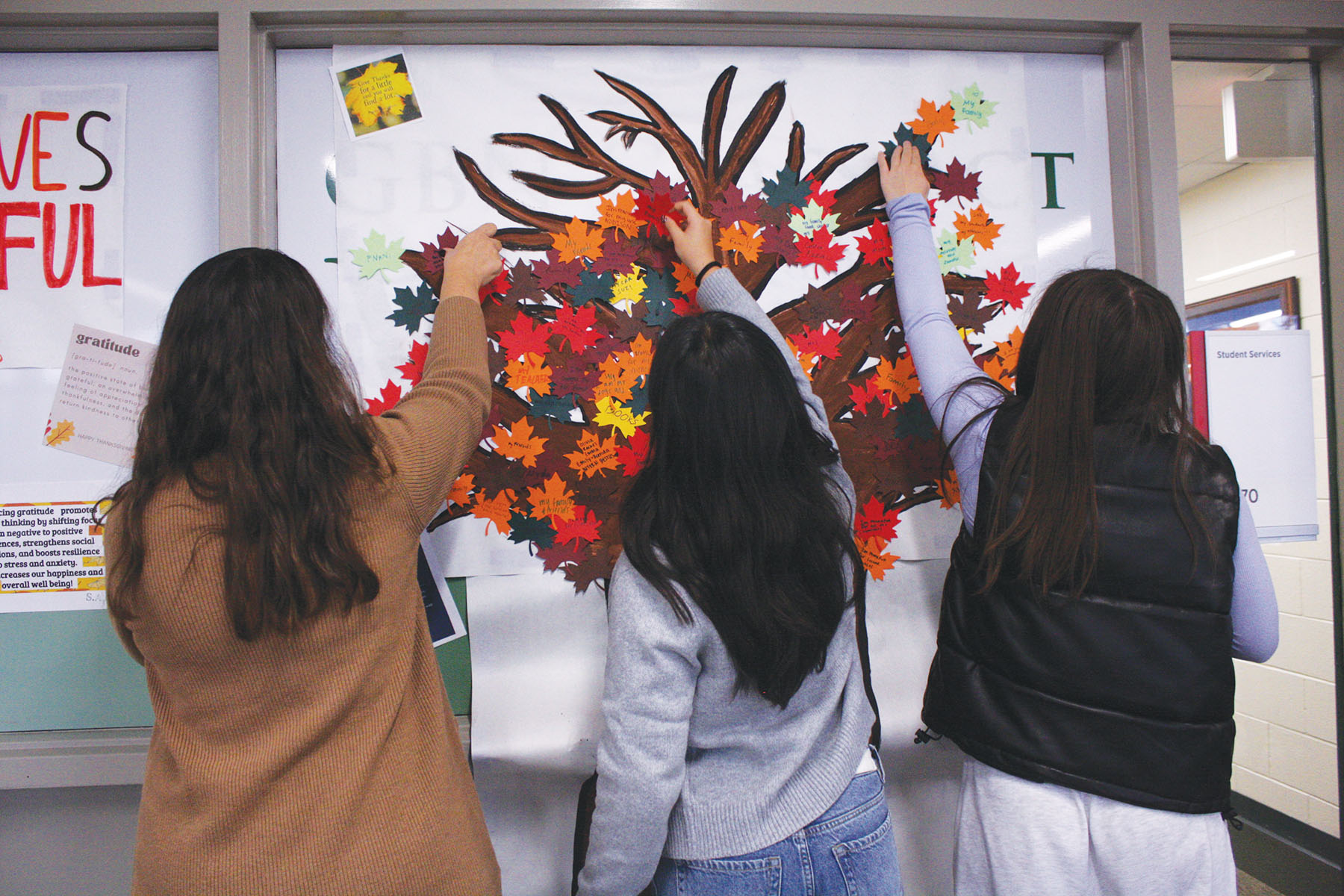 Mind Matters sponsor Christina Seaborg and juniors Stella Hyun and Vivian Majewski (left to right) place leaves on the Gratitude Event tree near the entrance to Student Services. Lack of sunlight during the winter months may lead to symptoms of seasonal affective disorder.