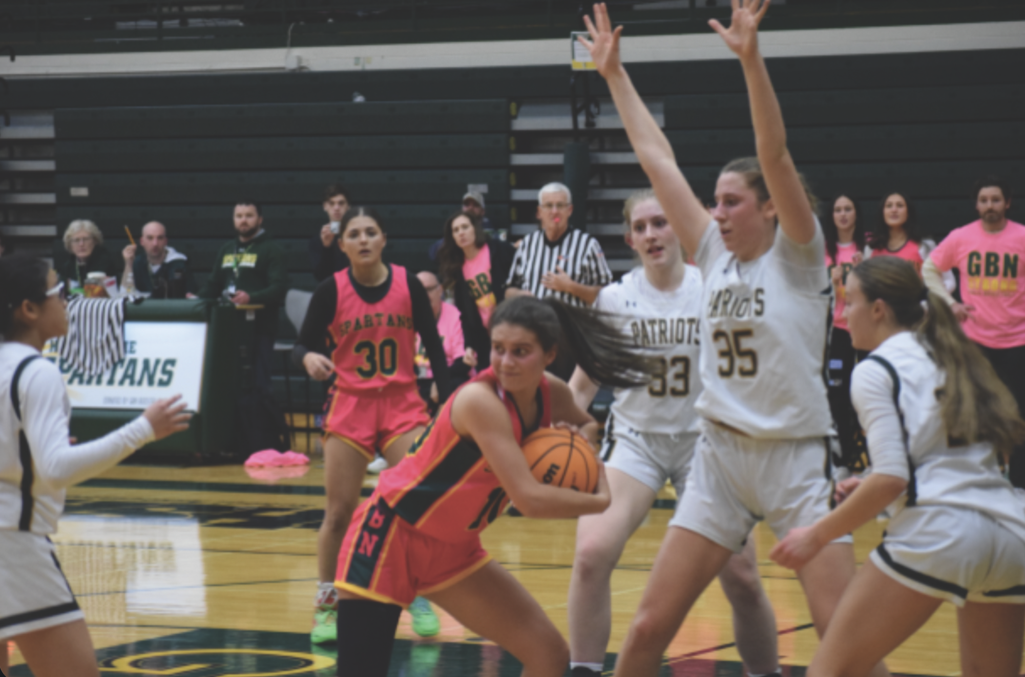 During the varsity girls basketball cancer awareness game against Stevenson on Jan. 20, junior Paige Giannoulias draws multiple Patriot defenders. Although the Spartans lost 54-47, the game raised over 3,000 dollars for the cause. 