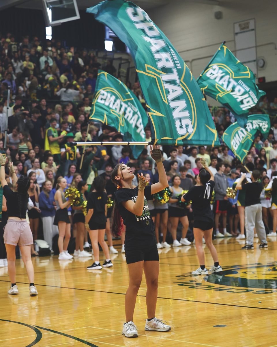 Performing in the first color guard routine of the season, senior Sophia Klein throws an angle toss with her flag. Using skills from diverse athletic backgrounds, like martial arts and gymnastics, color guard members are able to create unique choreography.